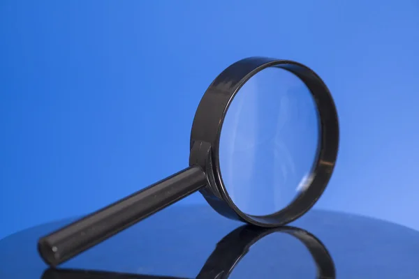 Magnifying glass on blue background — Stock Photo, Image