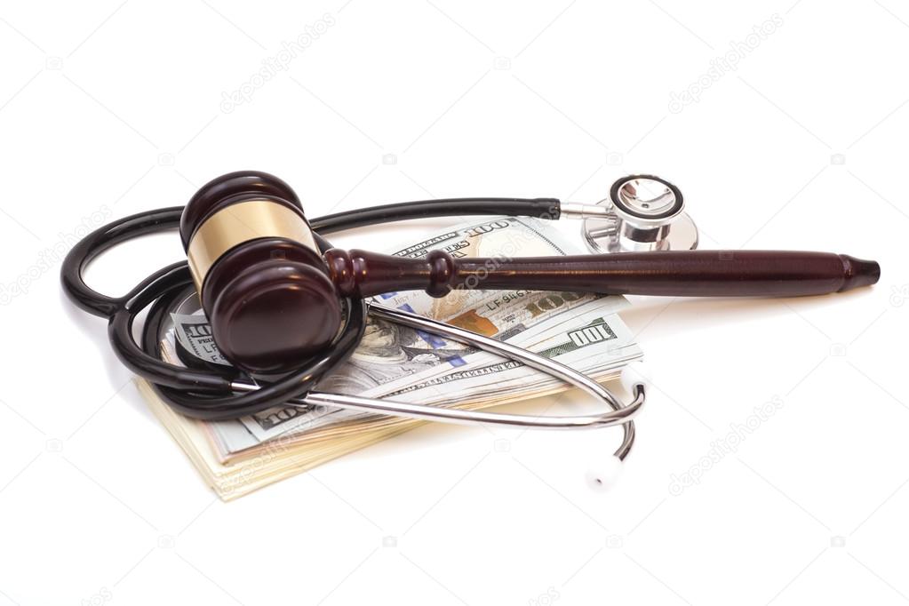 Stethoscope with judge gavel and dollar banknotes on white backg