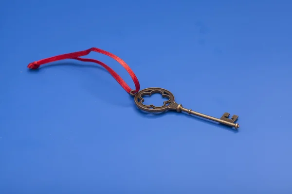 Schlüssel zum Erfolg mit roter Schleife auf blauem Hintergrund — Stockfoto