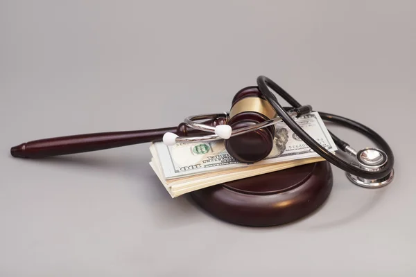 Stethoscope with judge gavel and dollar banknotes on gray — Stock Photo, Image