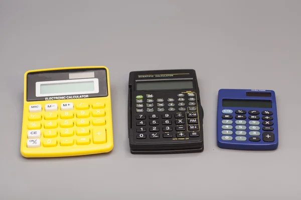 Three calculators isolated on gray background — Stock Photo, Image