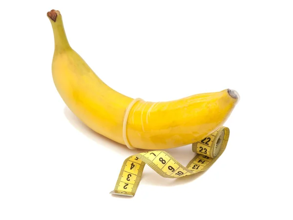Banana com preservativo e fita métrica isolada em branco — Fotografia de Stock