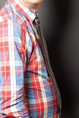 Adam gri arka plan üzerinde siyah kravat ile damalı gömlek giymiş