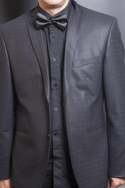 Man in pak Checkered en zwart en zwart strikje op grijze backgr — Stockfoto
