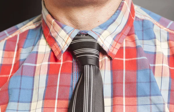 Чоловік одягнений з картатою сорочкою з чорною краваткою на сірому фоні — стокове фото