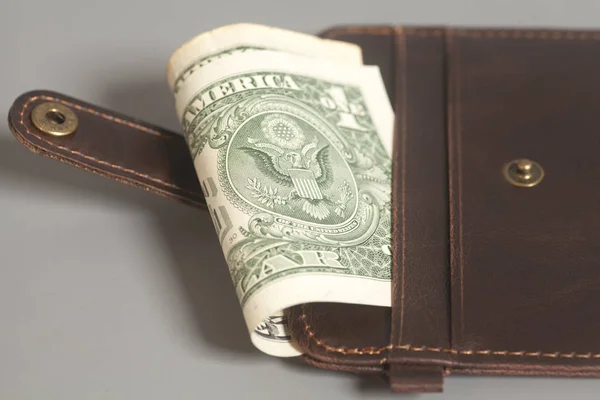 Carteira de couro marrom com um dólar em fundo cinza — Fotografia de Stock