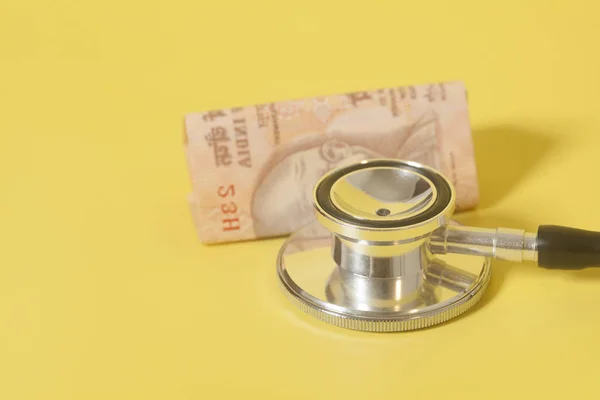 Stetoscopio e indiana 10 note di rupia su fondo giallo — Foto Stock