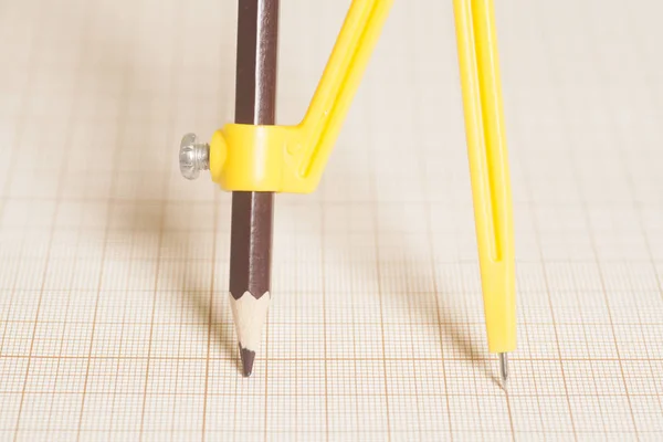 Bussola di disegno gialla su carta millimetrata — Foto Stock