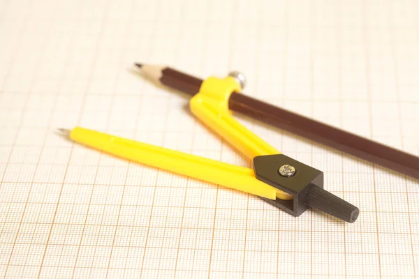 Yellow Drawing compass on graph paper — Stock Photo, Image