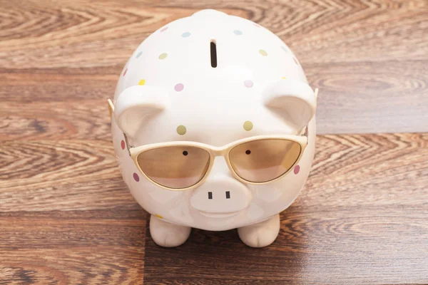 Piggy Bank com óculos de sol em fundo de madeira — Fotografia de Stock