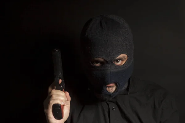 criminal bandit man wearing in balaclava holds a gun in his hand