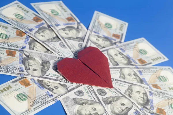 Papel vermelho origami coração e notas de dólar no fundo azul — Fotografia de Stock