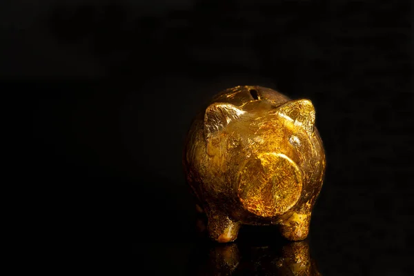 Goldenes Sparschwein auf schwarzem Hintergrund — Stockfoto