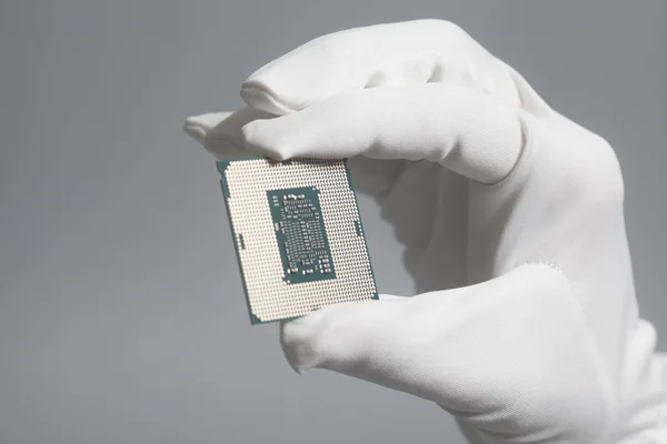 Mão na luva branca segurando um processador de computador CPU microchip — Fotografia de Stock