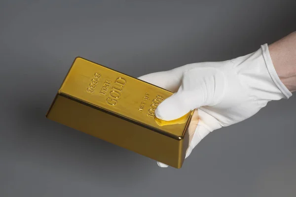 Mens beyaz eldiven külçe altının tutan el