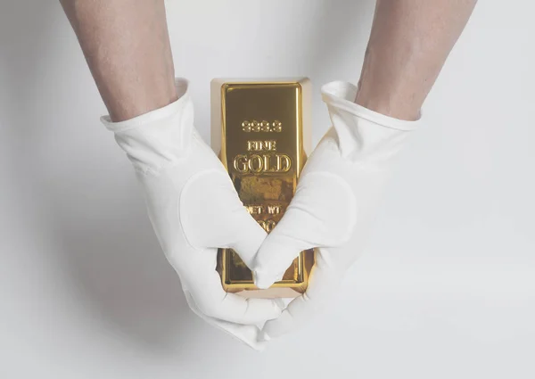 Mano da uomo in guanti bianchi con un lingotto d'oro — Foto Stock