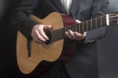 Muž v černém obleku s akustickou klasickou kytaru