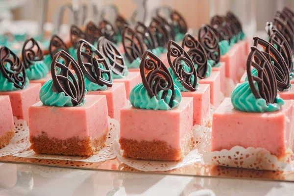 Detail fotografie svatební koláčky umístěné na skleněná kostka na dezert tabulky na recepci, růžová hnědá barevná paleta — Stock fotografie