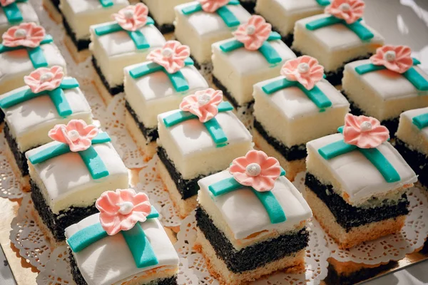 Detail fotografie svatební koláčky umístěné na skleněná kostka na dezert tabulky na recepci, růžová hnědá barevná paleta — Stock fotografie