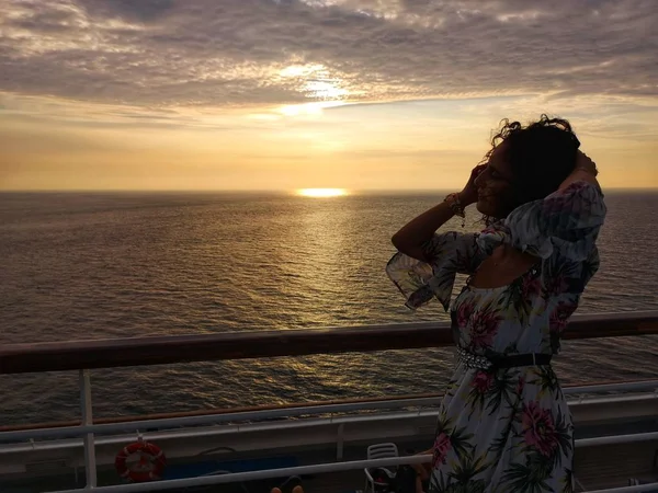 beautiful woman admires sunset from cruise ship