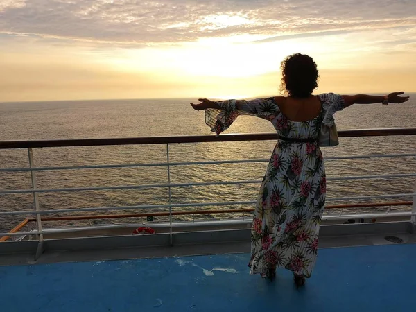 beautiful woman admires sunset from cruise ship