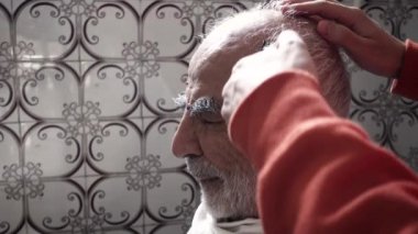 80 yaşındaki yaşlı Türk Müslüman adam 1980 'lerden kalma klasik banyosunda saçını kestiriyor.