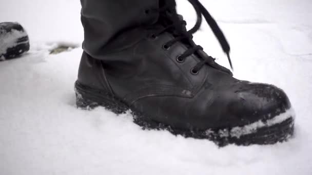 スローモーションで雪の上に戦闘ブーツの手順を身に着けている男の右の角度 — ストック動画