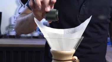 Barista el değirmeninden Chemex 'e kadar taze kahve dolduruyor.