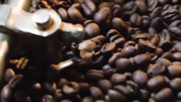Rastreando el brazo mecánico que mezcla granos de café asados en bandeja de enfriamiento — Vídeo de stock
