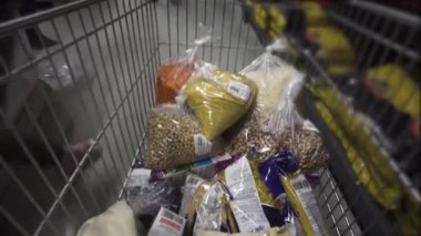 Süpermarketin tramvayında gezinmek. Erkek eller süpermarket vagonundan bir paket fasulye alır. Yiyecek için zıplarken Corona virüsünün neden olduğu karantina için endişelenirler.