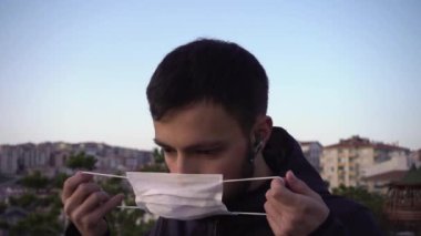 Korona virüsünden korunmak için maske takan endişeli genç bir adam.