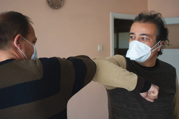 Koronavirüs yüzünden dirsek tokuşturan maskeli iki üst düzey Türk.