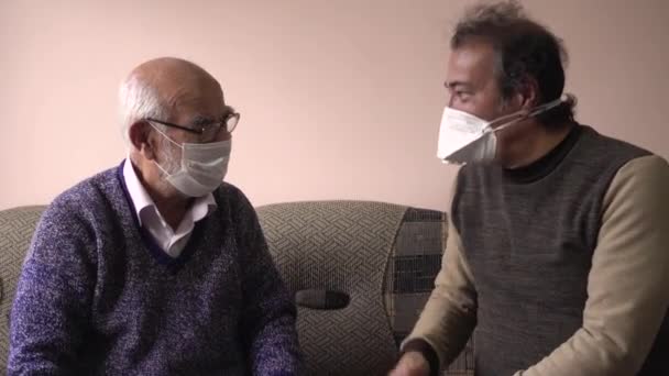 トルコ人の父と息子のサイドビューマスクを身に着けているコロナウイルスについてチャット — ストック動画