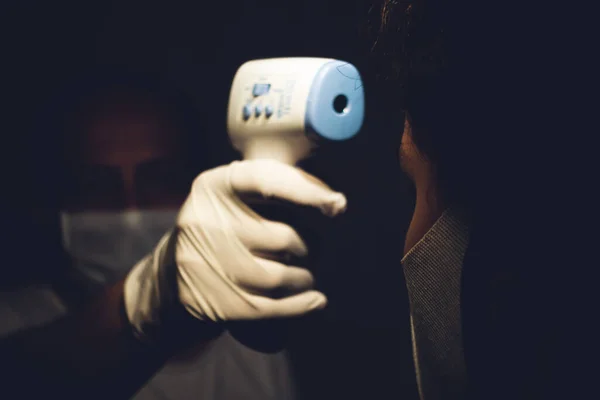 Старший Медицинский Работник Измеряет Температуру Тела Молодого Человека Инфракрасным Термометром — стоковое фото