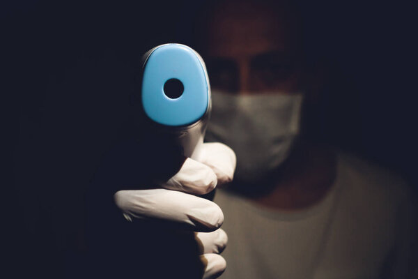 Male Health Worker Points Out a Infrared Thermometer to the camera Point of View- Dark Scary