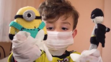 Pijamalı, cerrahi maske takmış, amigurumi oyuncaklarıyla oynayan neşeli küçük Türk çocuk.