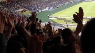 Taraftarlar, güneşli bir günde stadyumdaki şampiyonluk maçında futbol kulübüne tezahürat edip destek veriyorlar.