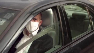 Güvenlik görevlisi sağlıklı bir sürücünün vücut ısısını kızılötesi termometreyle ölçüyor ve yoluna devam etmesini sağlıyor.