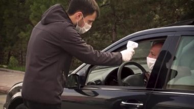 Güvenlik görevlisi sürücünün vücut ısısını ölçüyor ve devam etmesine izin veriyor.