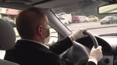 Cerrahi eldiven ve maske takan kıdemli Türk yetişkin, karantina altındaki boş sokaklarda araba sürüyor