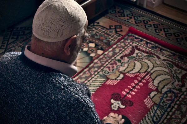 Çok yaşlı sakallı Türk erkek, 80 'li yaşlarda dua şapkası takıyor Ramazan ayında evinde namaz kılıyor.
