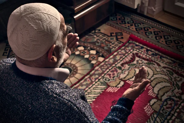 Çok yaşlı Müslüman bir adam 80 'li yaşlarda evinde, kiliminde Allah' a dua ediyor.