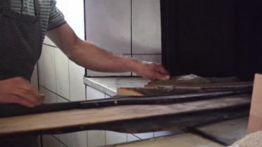 Fırın ustası fırını odunlarla besliyor ve fırıncı küreğinin yardımıyla iki ramazan ekmeğini götürüyor.