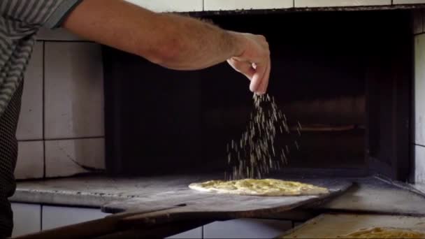 Koki Pria Menuangkan Wijen Pada Roti Ramadan Dan Mendorongnya Dalam — Stok Video