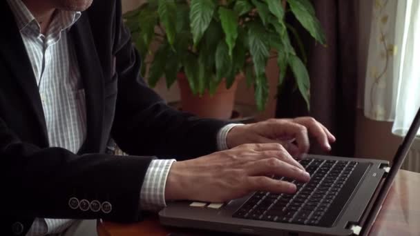 高级成年男性手拉手 身穿智能休闲装 在家中工作 用笔记本电脑打字 背景为工厂 — 图库视频影像