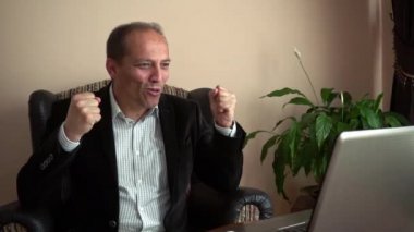 Yavaş çekim çok mutlu ve gülümseyen bir iş adamı. Evden güzel kıyafetler giyerek geliyor. İş arkadaşlarıyla yaptığı bir video konuşmasında iyi haberler alıyor.