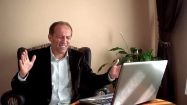Ağır çekim işadamı, iş arkadaşlarıyla evdeki bilgisayarını kullanarak yaptığı bir video konferansında iflas haberini aldıktan sonra çok üzgün ve hayal kırıklığına uğramış bir şekilde tepki veriyor.