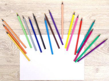 Ahşap bir grupta kağıt üzerinde renkli kalemler.