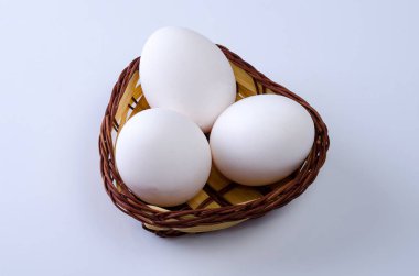 Gri arka planda tavuk yumurtaları olan bir sepet üzüm.