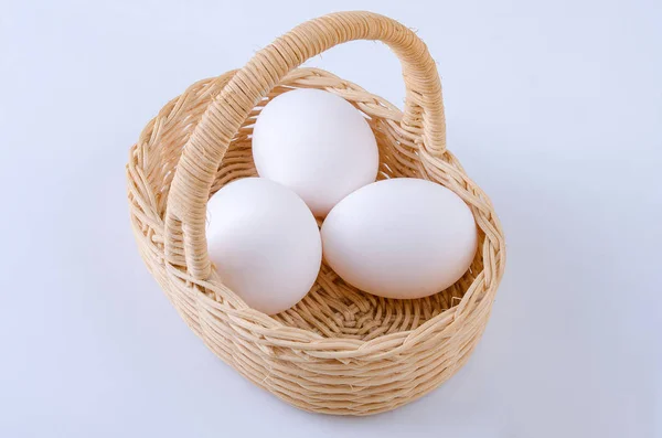 Gri arka planda tavuk yumurtaları olan bir sepet üzüm.